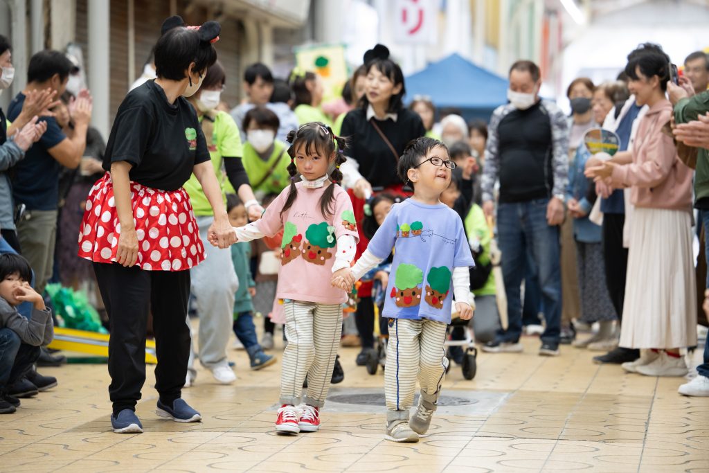 商店街のランウェイを誇らしげに歩く子どもたち